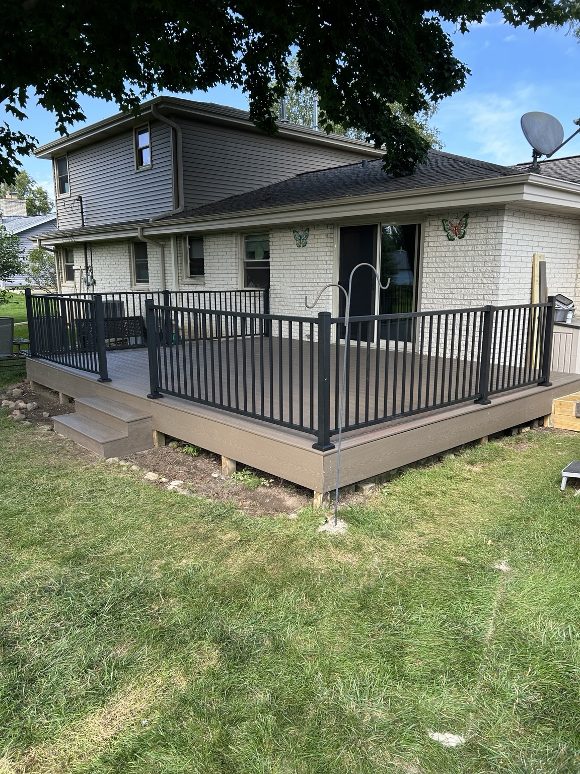 After: the same home with composite deck boards, black railings, and matching fascia