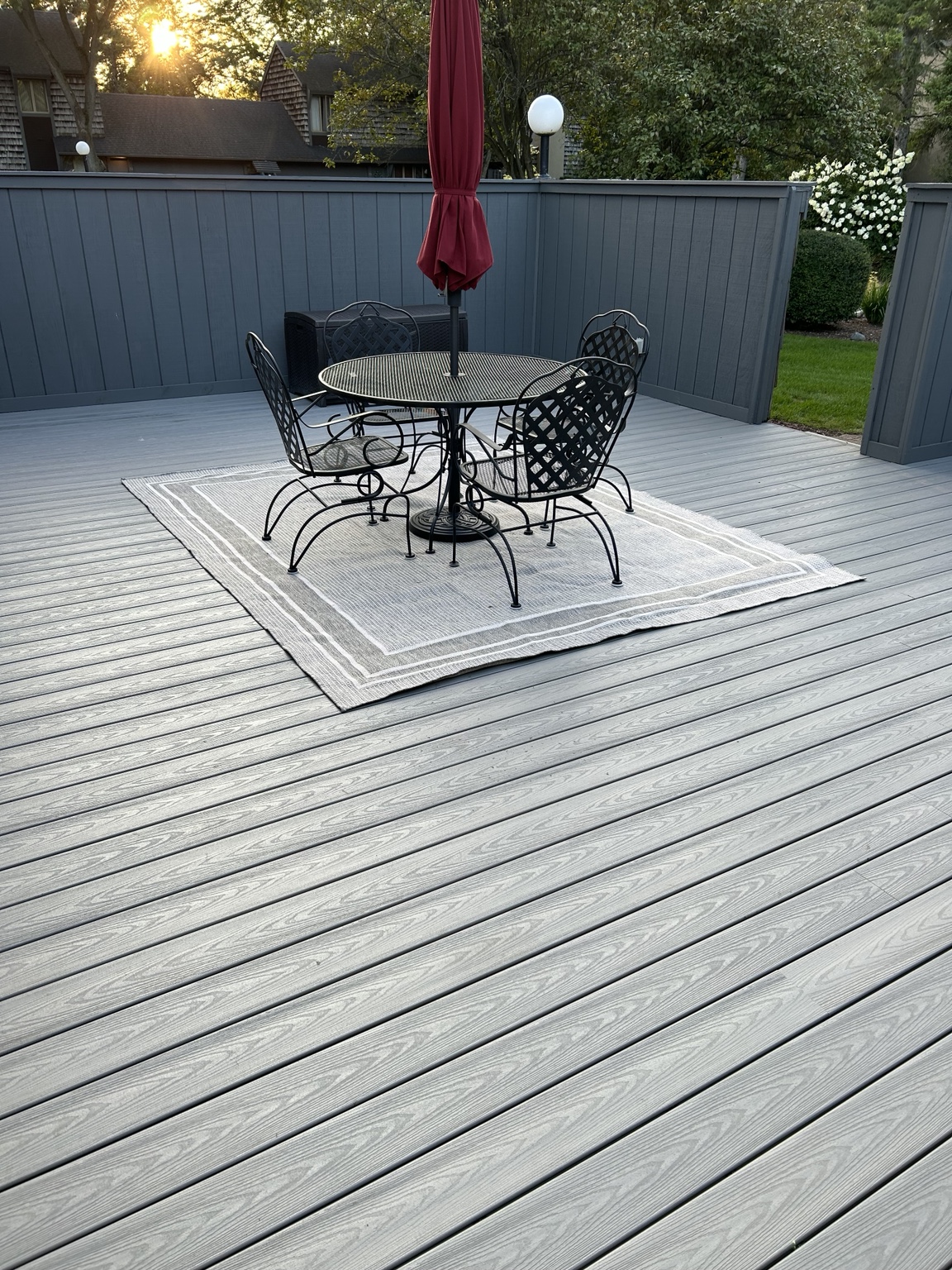 Completed gray composite deck with outdoor dining furniture in evening sunlight