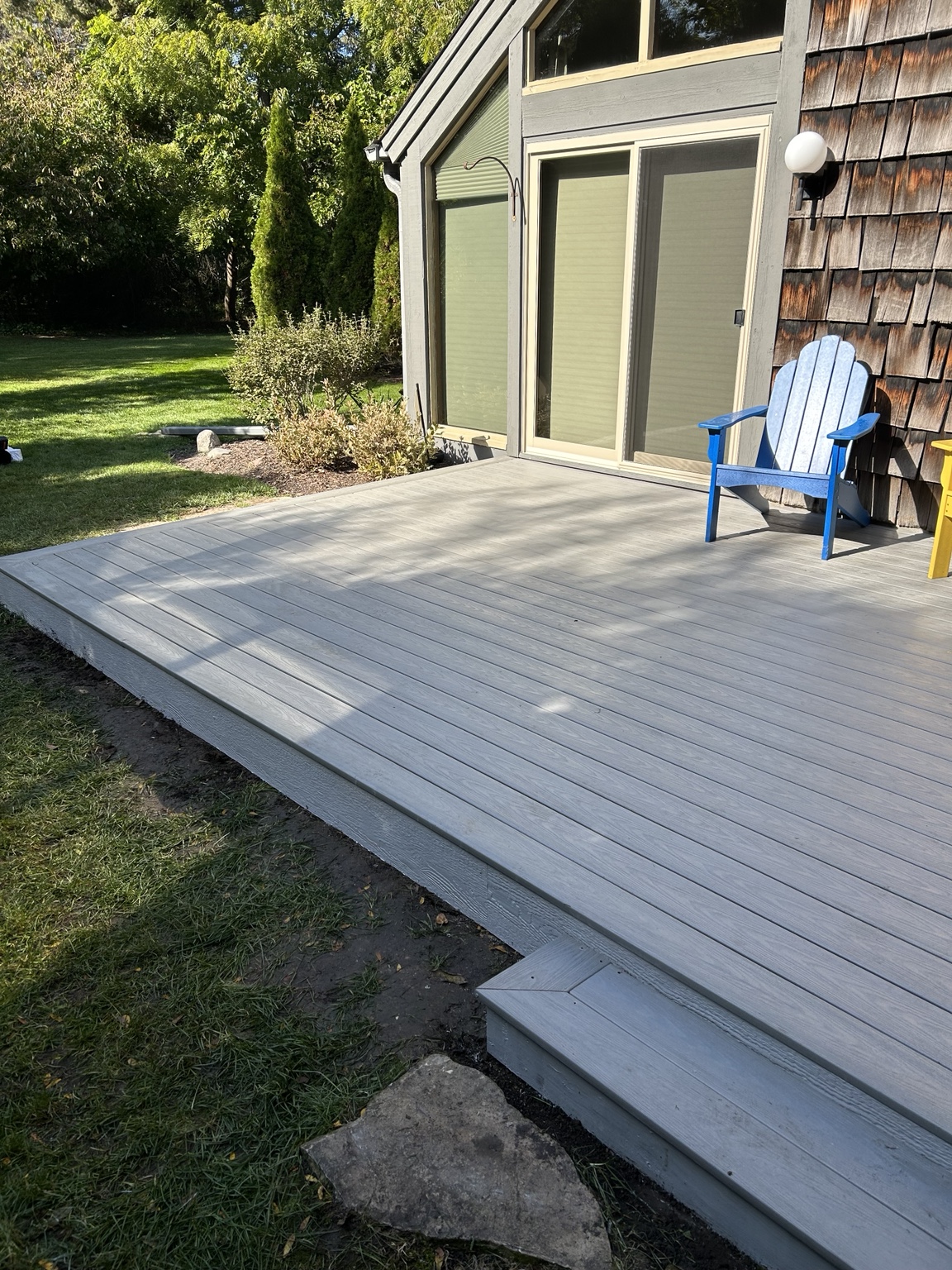 Gray composite deck with picture-frame edging and a matching low step beside a blue chair