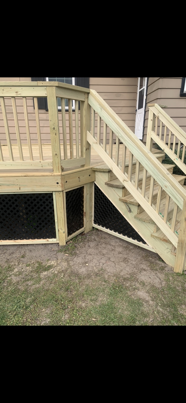 Wood deck stairs and railings beside black lattice skirting.